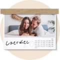 Personalizowany kalendarz ścienny CEWE na czerwiec z ujęciem pary w sypialni, zawieszony na drewnianym uchwycie w minimalistycznym stylu