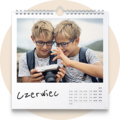 Kalendarz ścienny na czerwiec ze zdjęciem dwóch chłopców w pasiastych koszulkach oglądających wspólnie aparat fotograficzny
