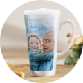 Latte macchiato w wysokiej filiżance ze zdjęciem dwóch przytulających się osób na tle nieba oraz napisem KUBEK na górze