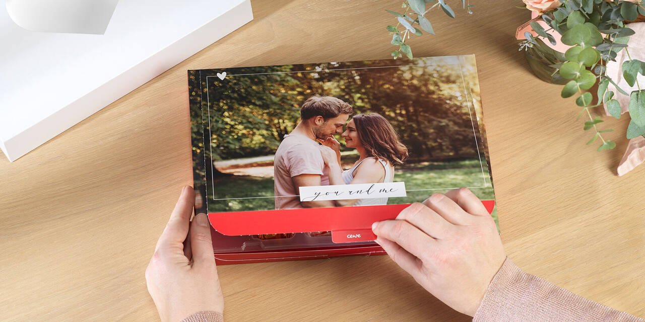 Dłoń otwiera pudełko ze zdjęciem. Na pokrywie widać zdjęcie pary. Obraz jest otoczony wzorem z napisem „Ty i ja”.
